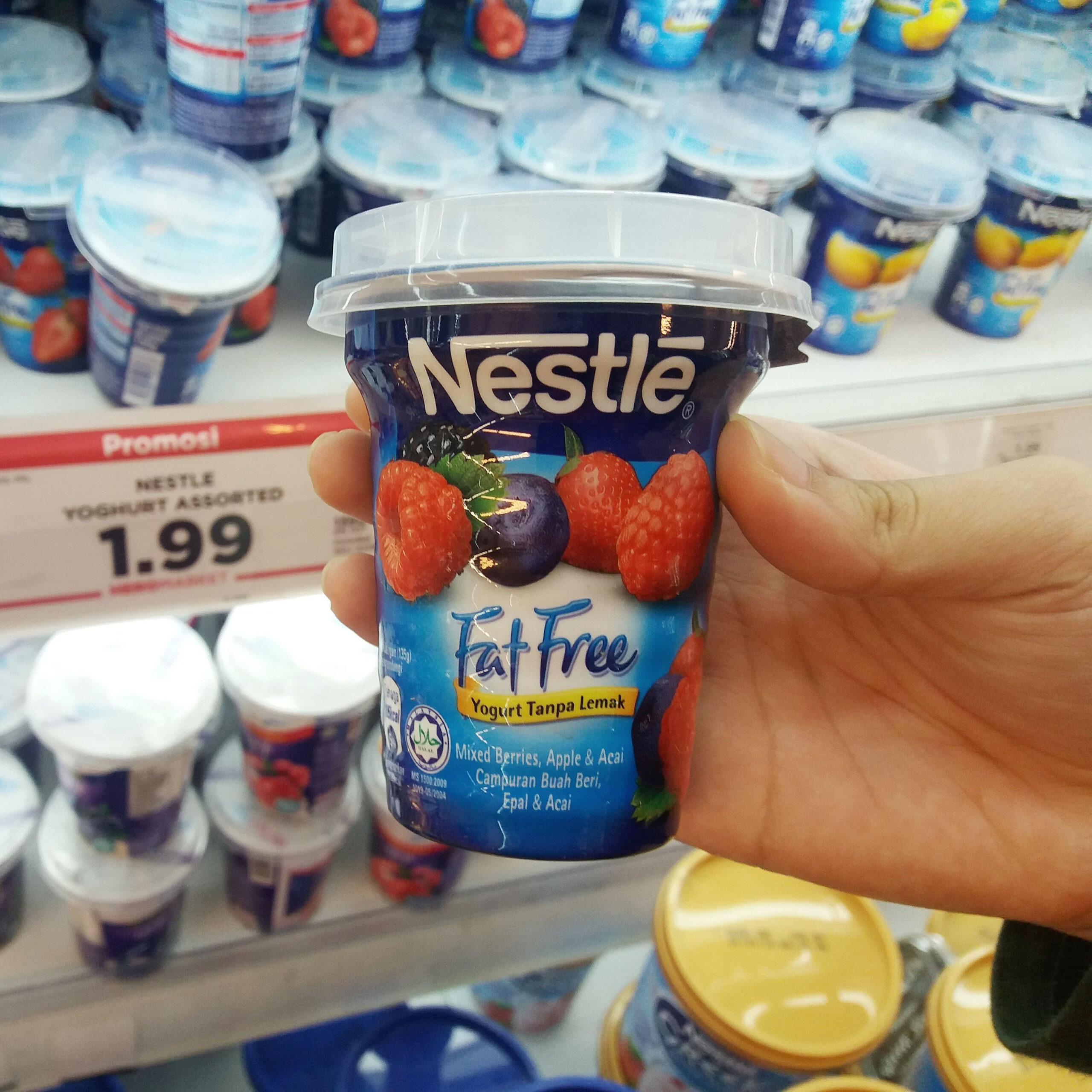 person holding low-fat nestle yogurt in grocery store