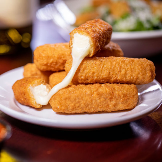 mozzarella sticks on plate with one open and oozing cheese