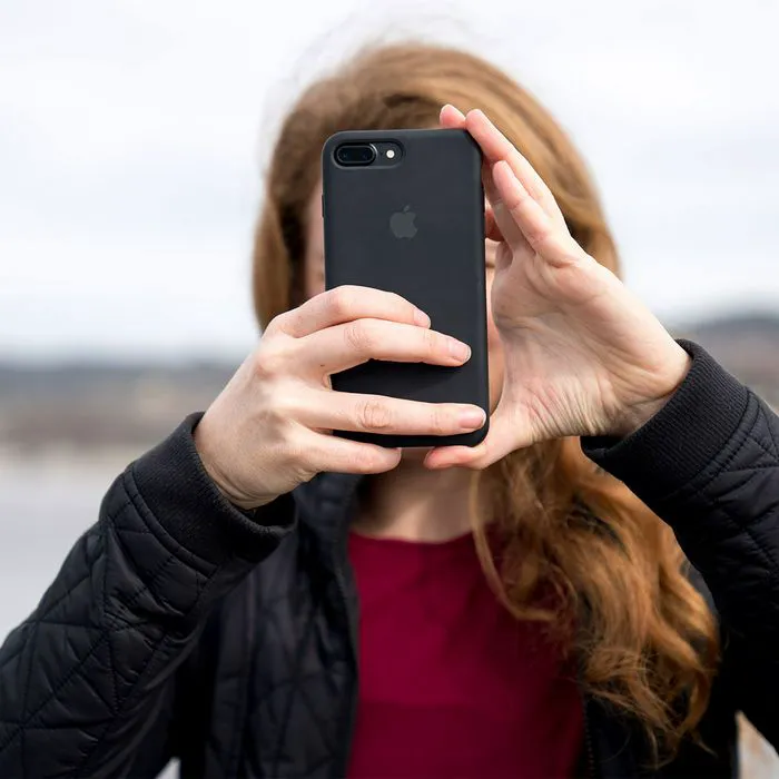 Redhead woman taking photos with her iPhone