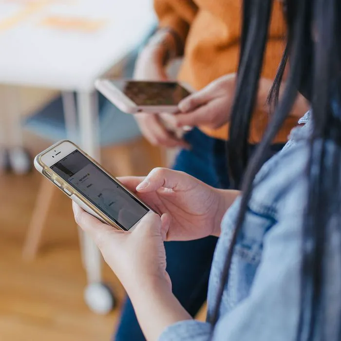 Two women using their iPhones together in a cafe