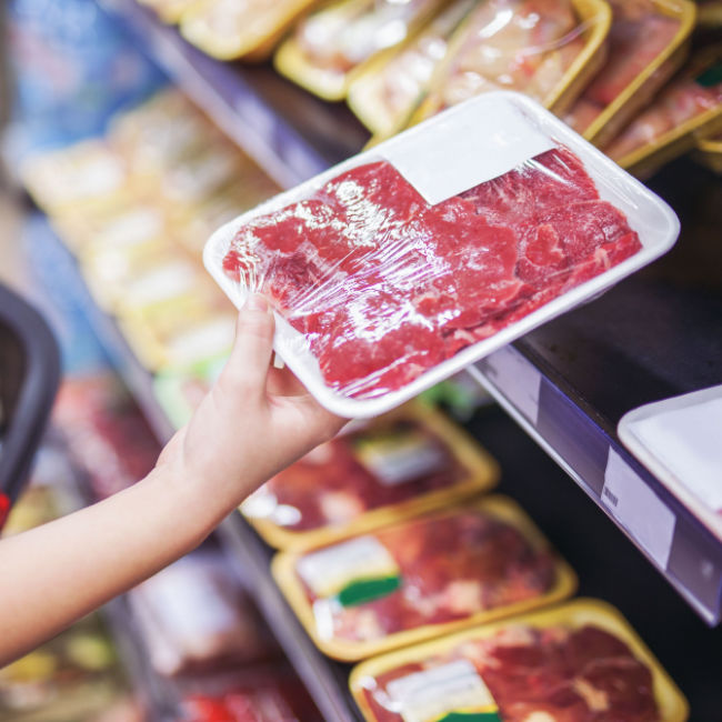 woman buying red meat at grocery store