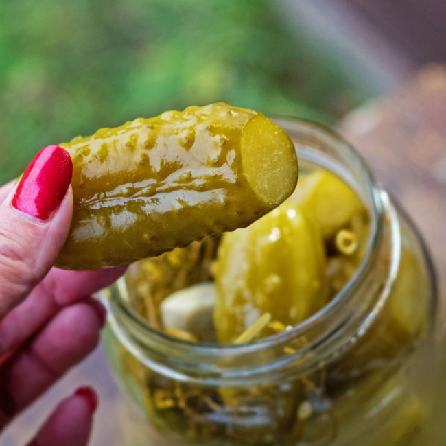 woman holding pickle from jar