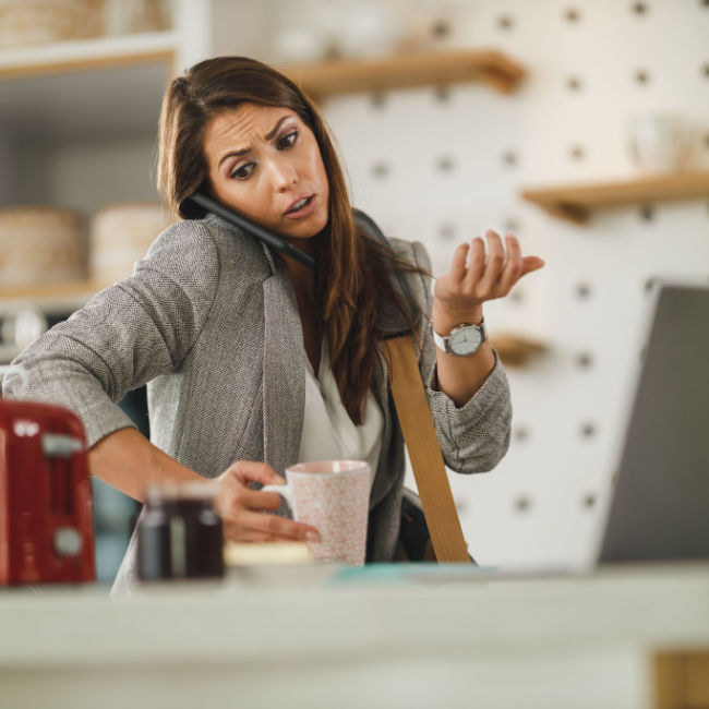 woman on phone and computer making coffee