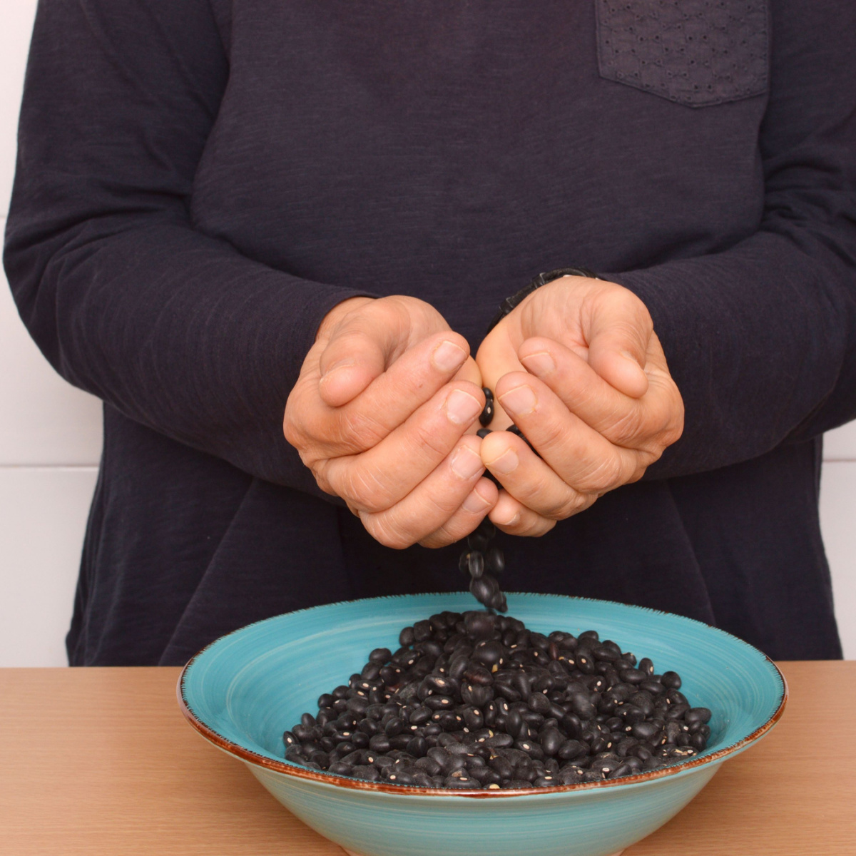 woman adding black beans to bowl in kitchen