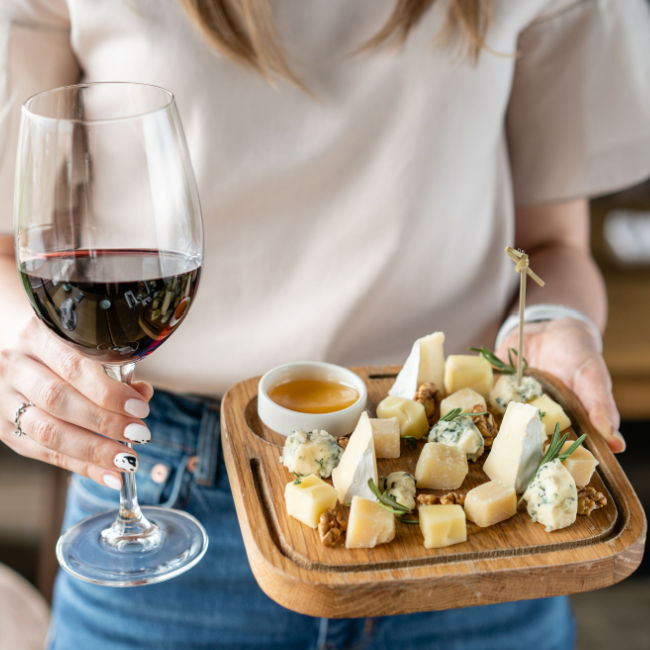 woman holding cheese board and glass of wine