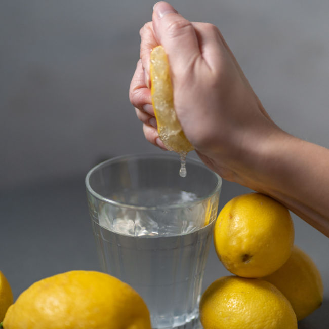 woman squeezing lemon into glass of water