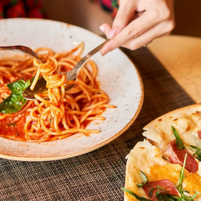 "Woman enjoying pasta and pizza meal"