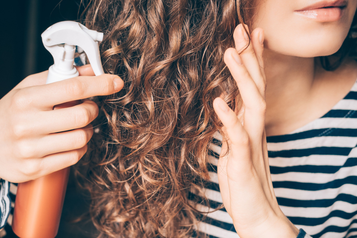 A woman putting texture spray in her hair.