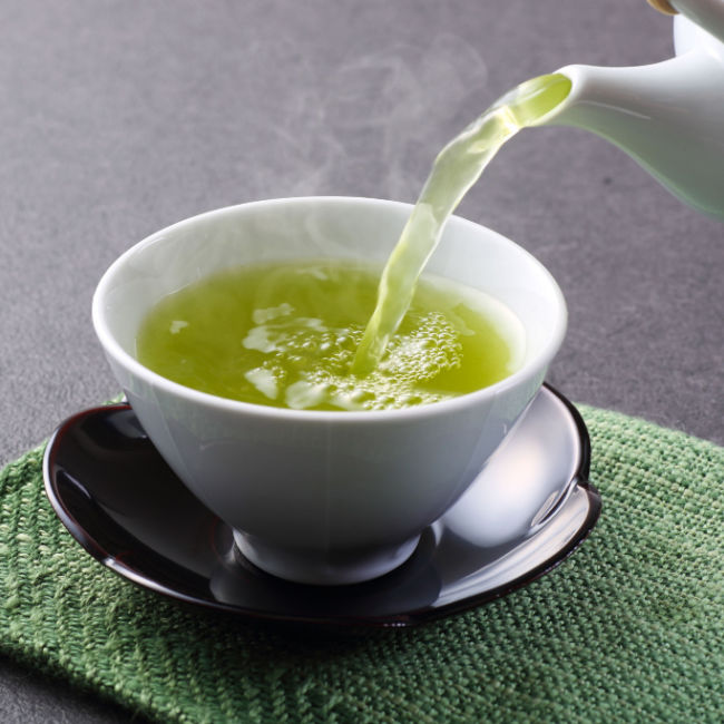cup of green tea being poured
