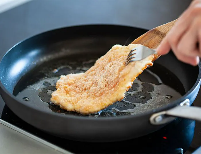 Person drying chicken in oil.