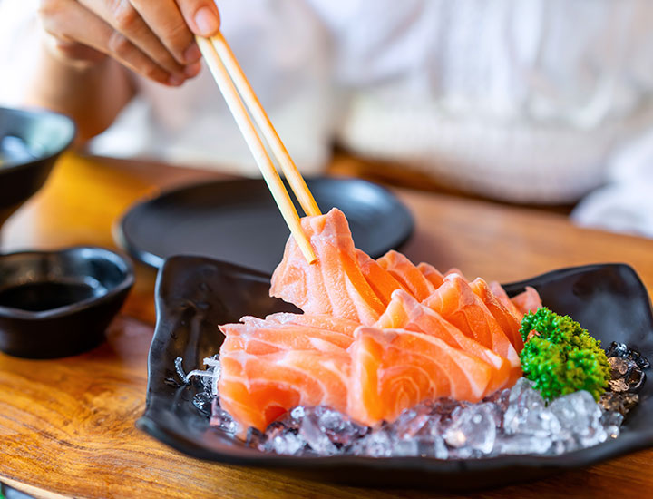 Person eating salmon sashimi.