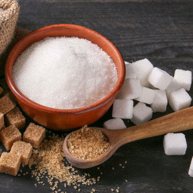 small bowl of refined white sugar surrounded by sugar cubes
