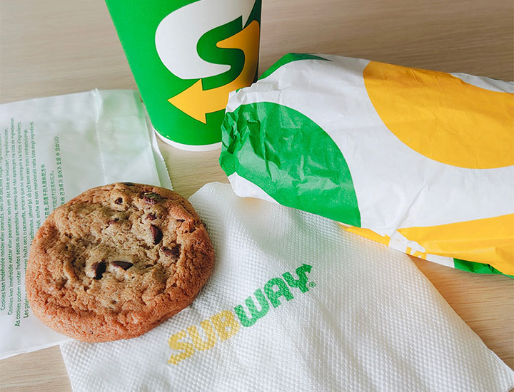 Subway sandwich and cookie on a table.