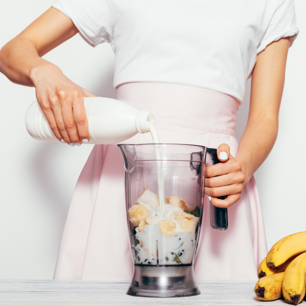 Someone pouring milk into blender.