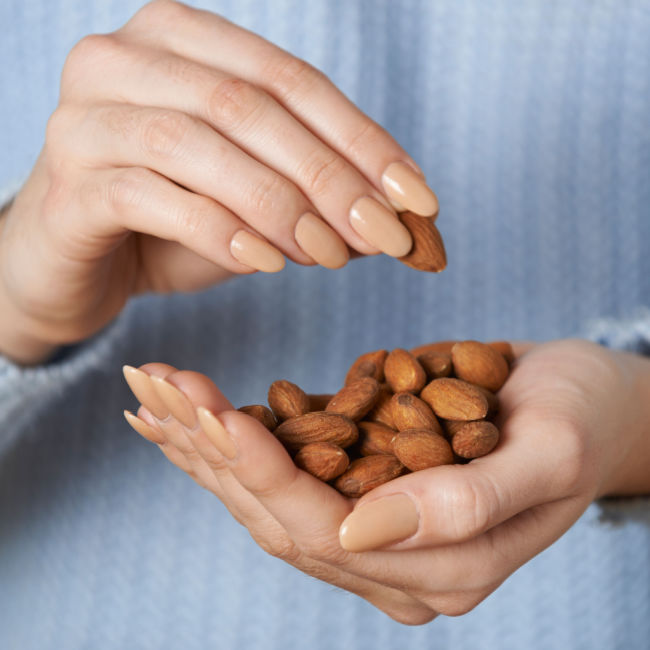 manicured hands holding handful of almonds