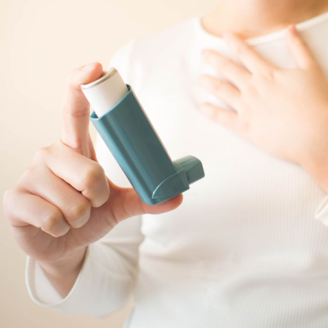 person holding inhaler with hand on chest