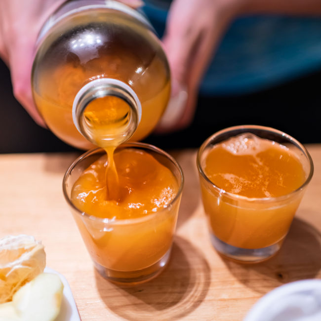 bottle of kombucha being poured into glasses