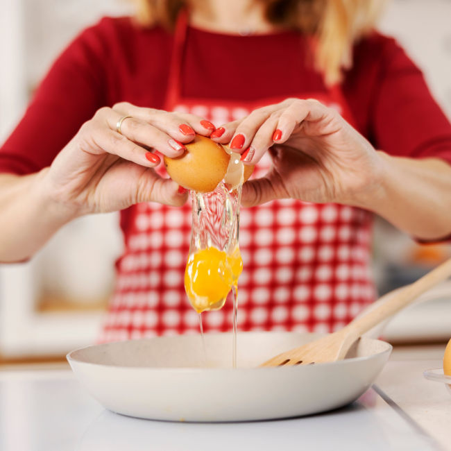 woman beating egg in pan