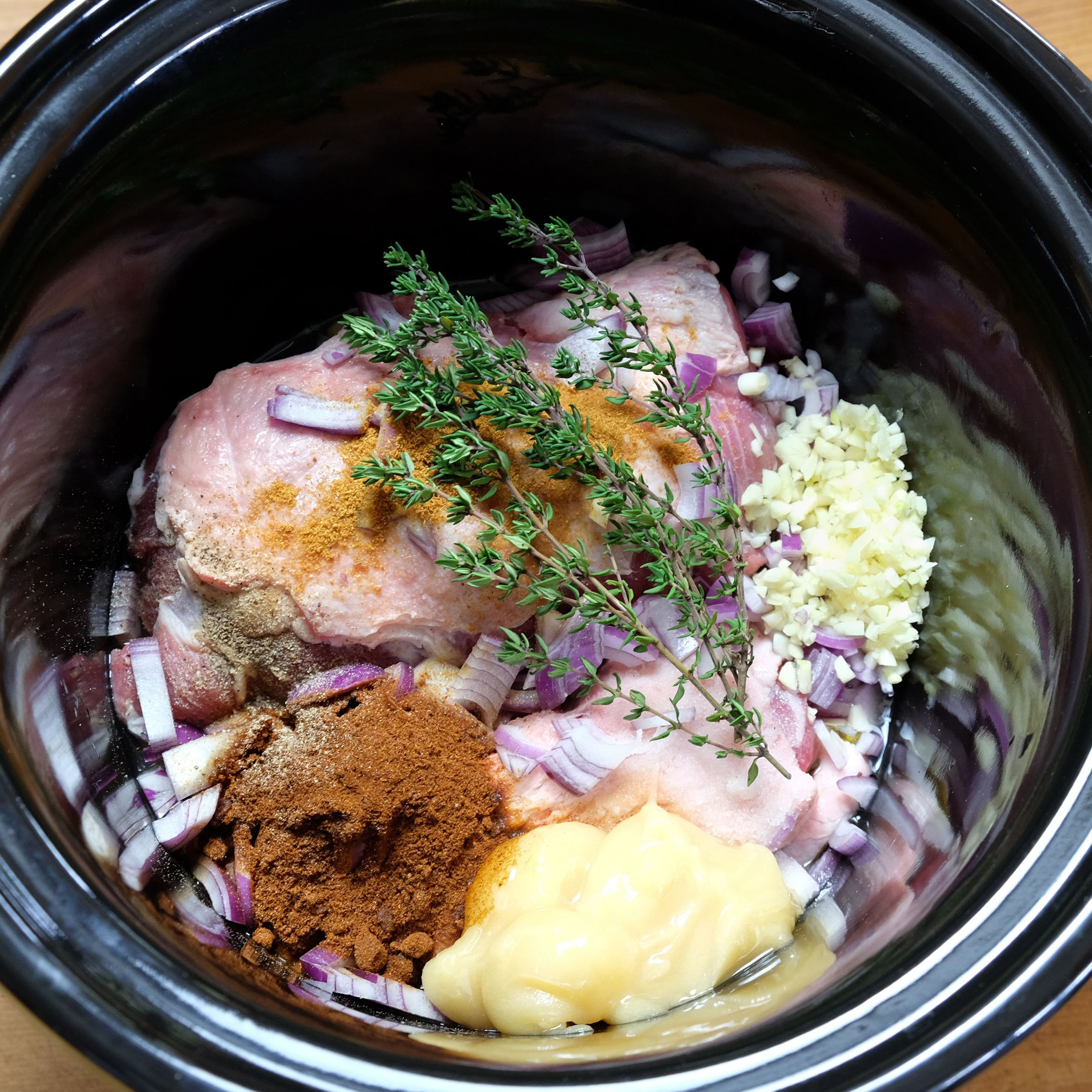 pork and seasoning and herbs in a slow cooker