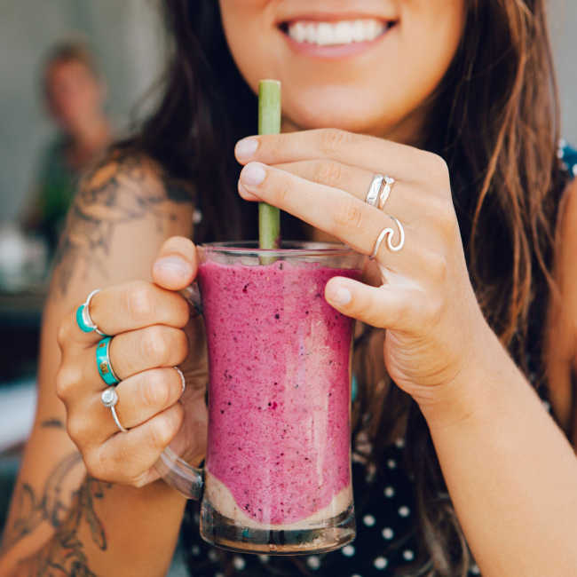 woman smiling holding smoothie with straw