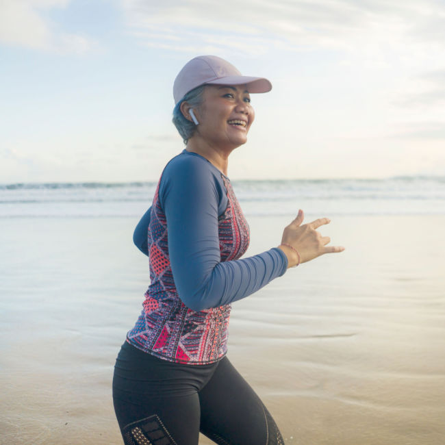 middle aged woman jogging on beach