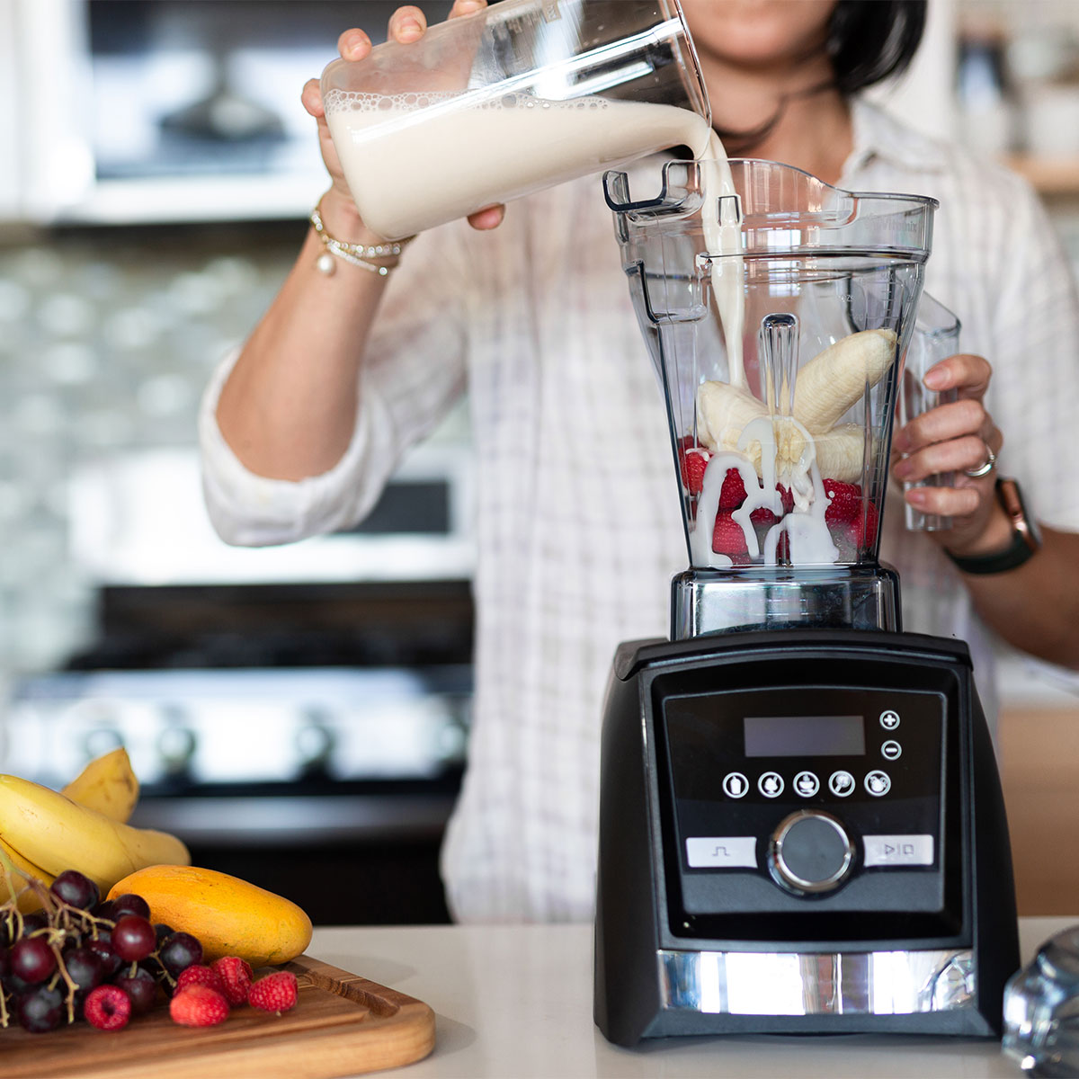 woman making a berry-banana smoothie in her kitchen