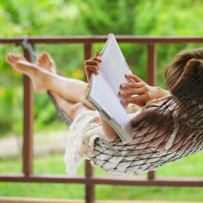 barefoot woman reading outdoors in hammock