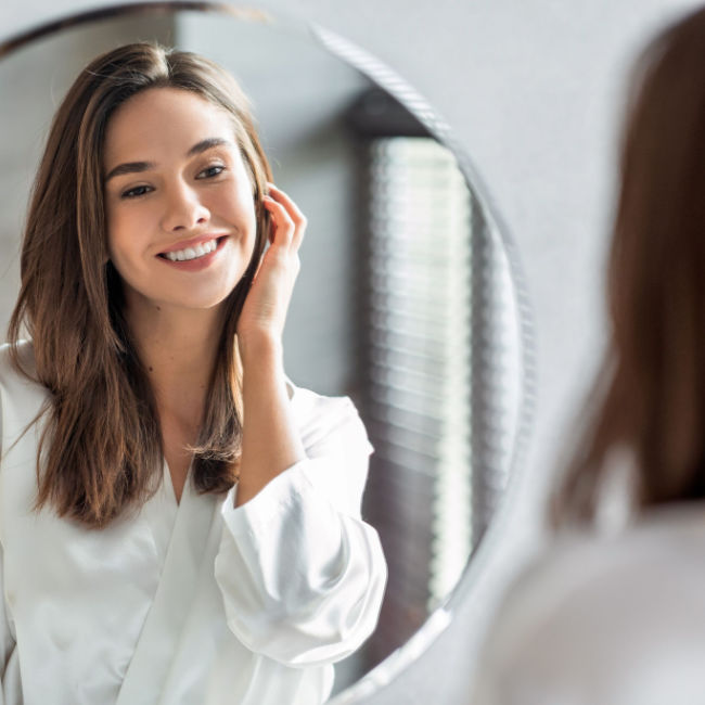 woman smiling at herself in the mirror
