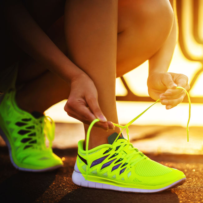 woman tying bright yellow running shoes
