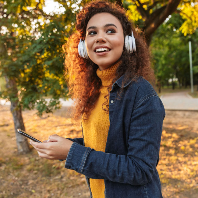 woman walking outside in the fall wearing over-ear headphones