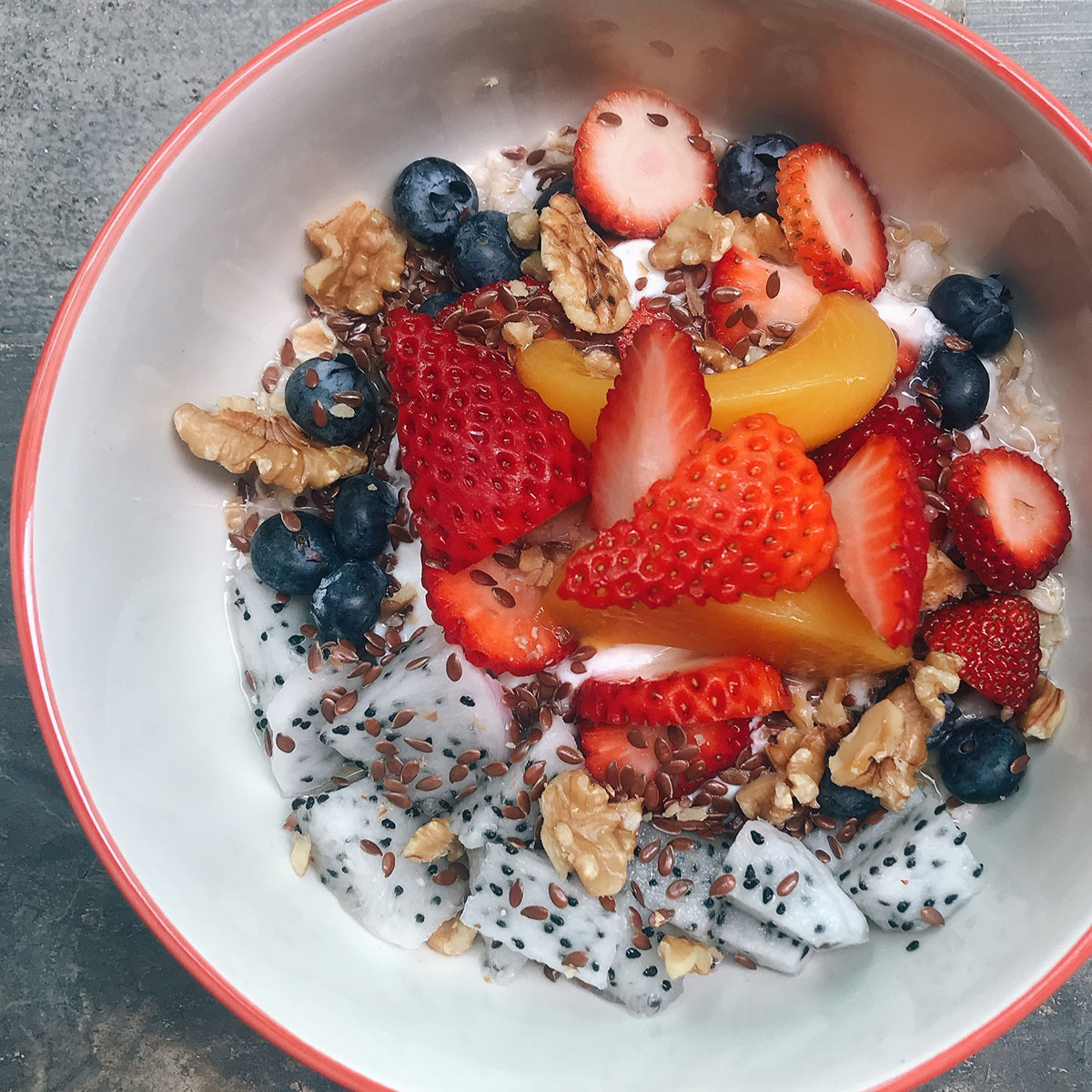 yogurt bowl topped with strawberries, blueberries, flaxseeds, walnuts