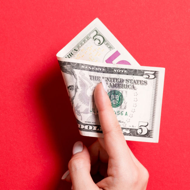 person holding folded 5-dollar bill between their fingers