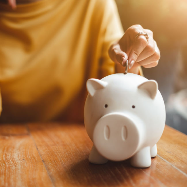 hand putting coin in piggy bank