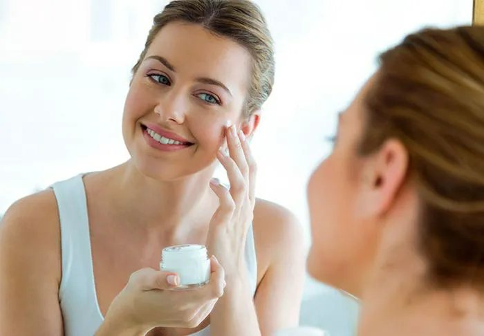 Woman applying moisturizer.