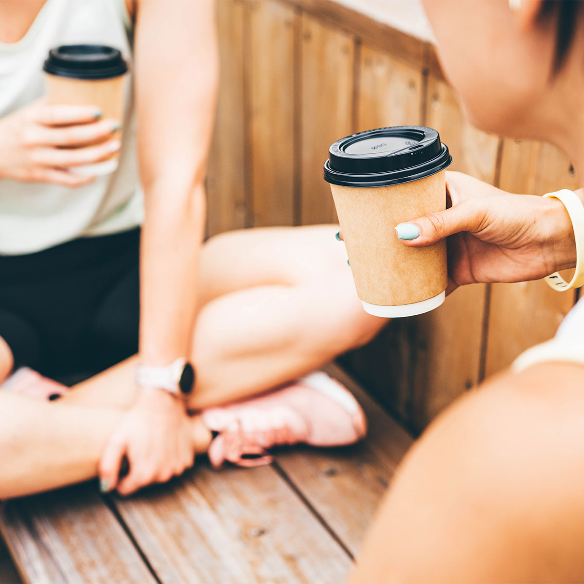 women drinking coffee outdoors after workout