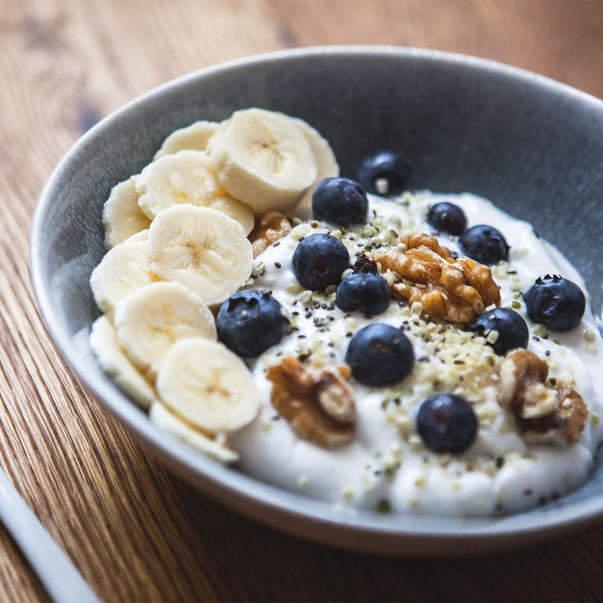 bowl of yogurt topped with walnuts, blueberries, and banana