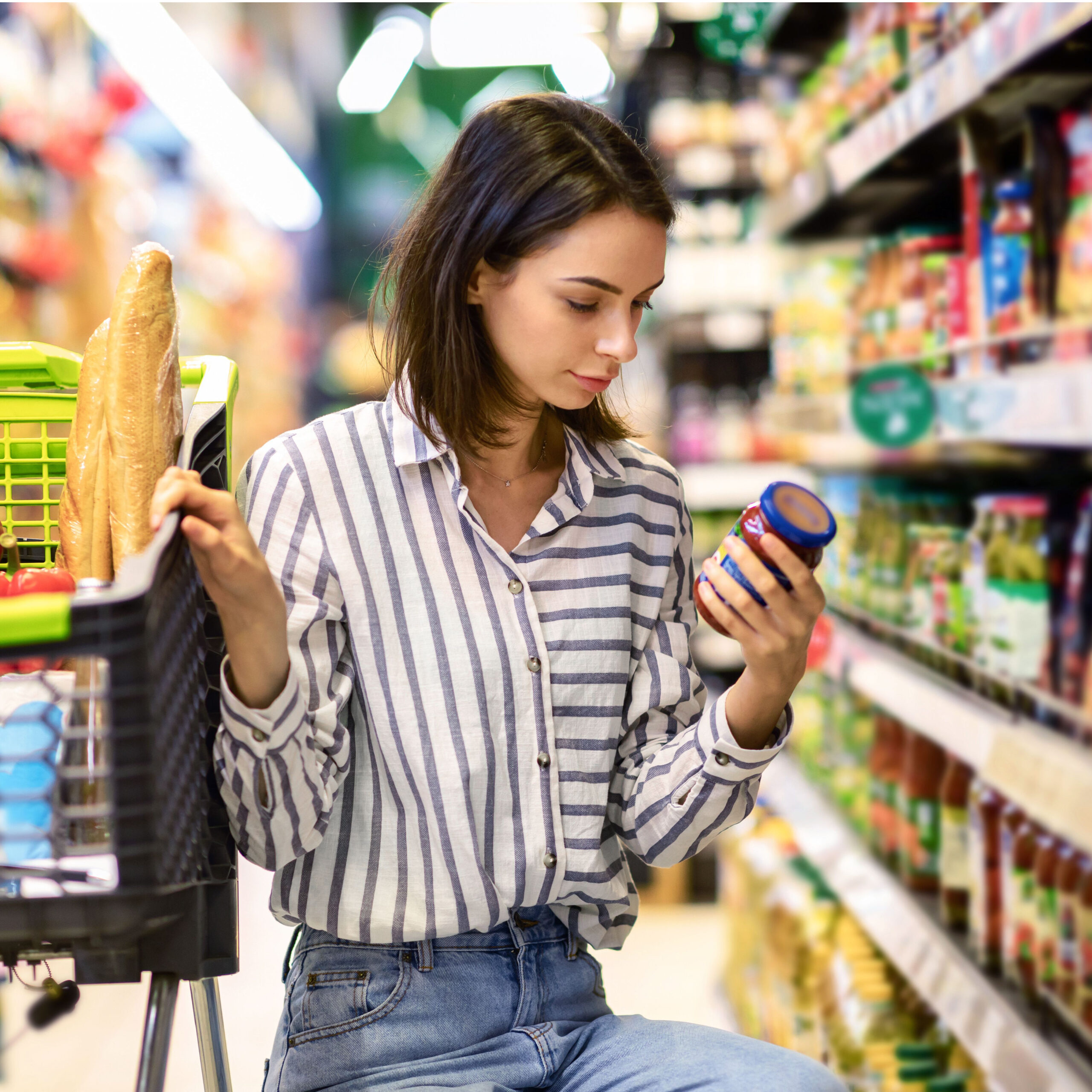 woman checking nutrition label of product in grocery store