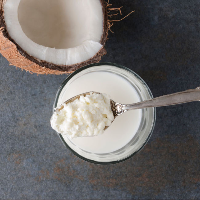 spoonful of coconut kefir over jar with coconut in background