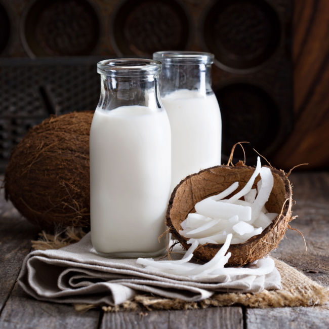 two glasses of coconut milk besides half a coconut