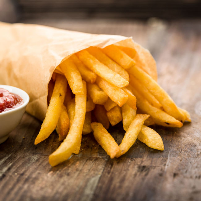 french fries in paper wrapping with side of ketchup