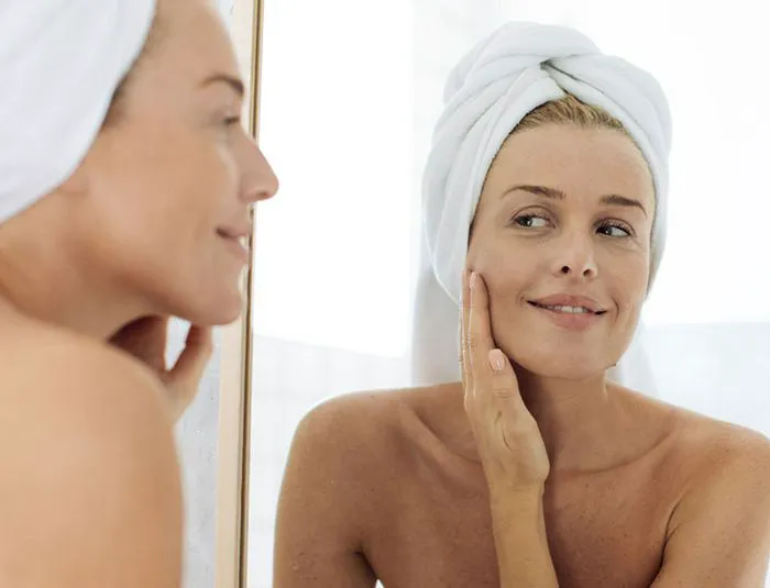"Woman looking in the mirror at her skin"