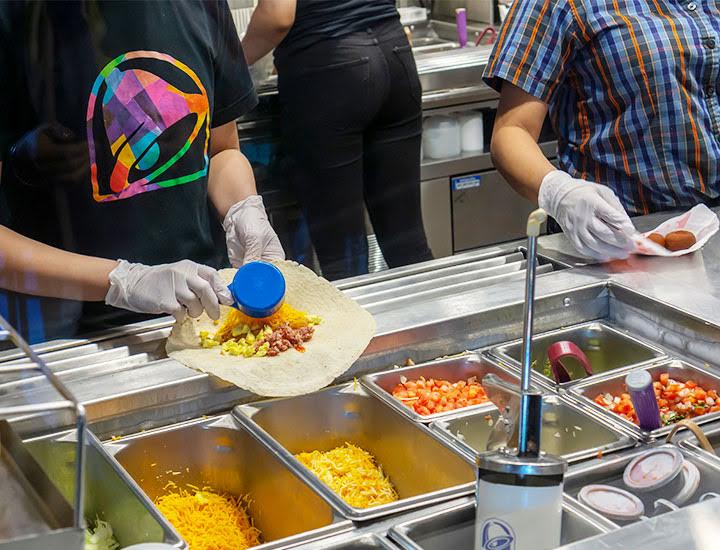 Taco Bell employees assembling a meal at a food station