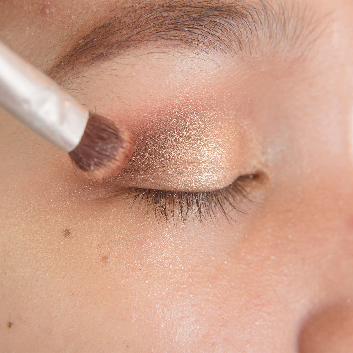 applying silver smokey glittery eyeshadow with brush to eyelid