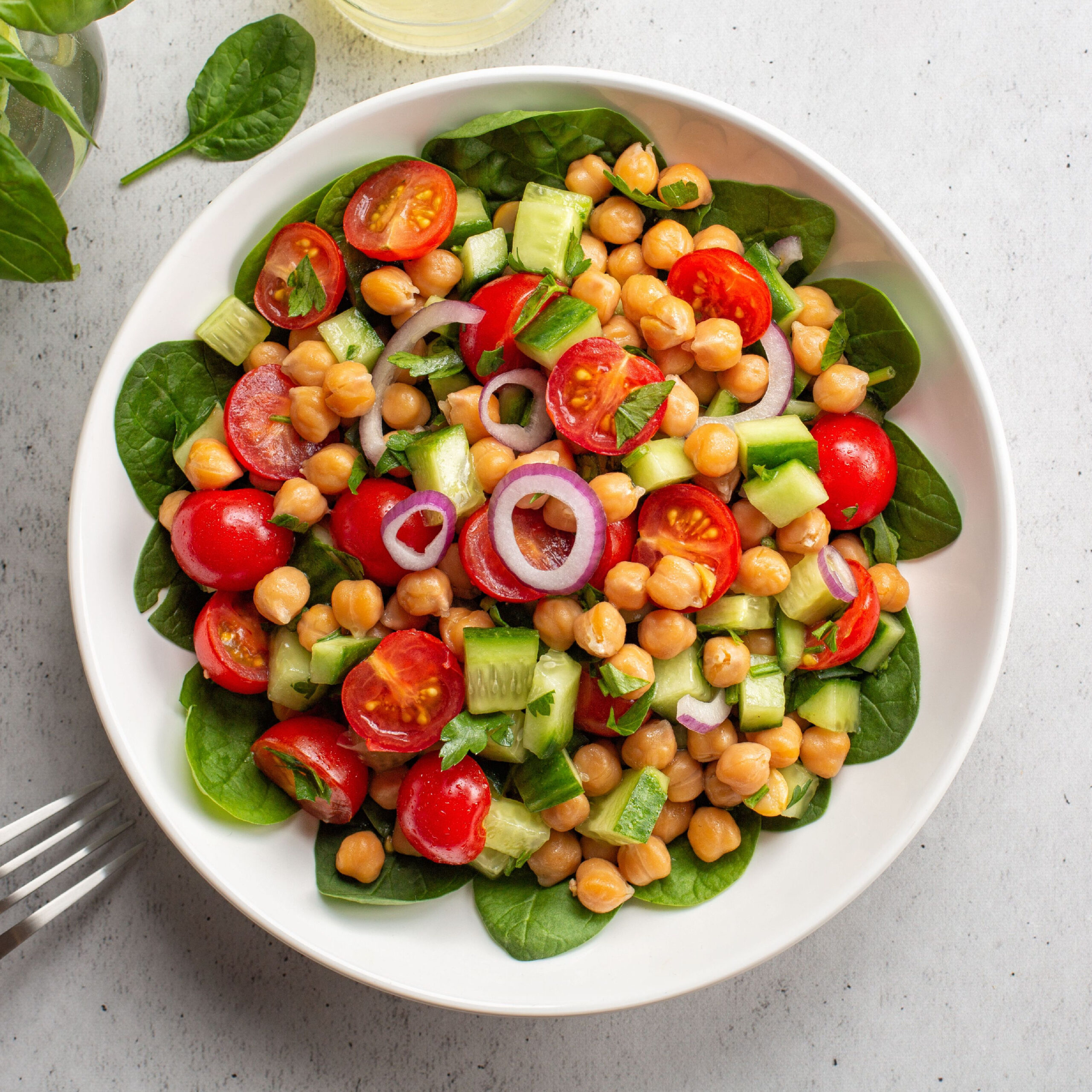 salad topped with cherry tomatoes, cucumber, chickpeas, red onion