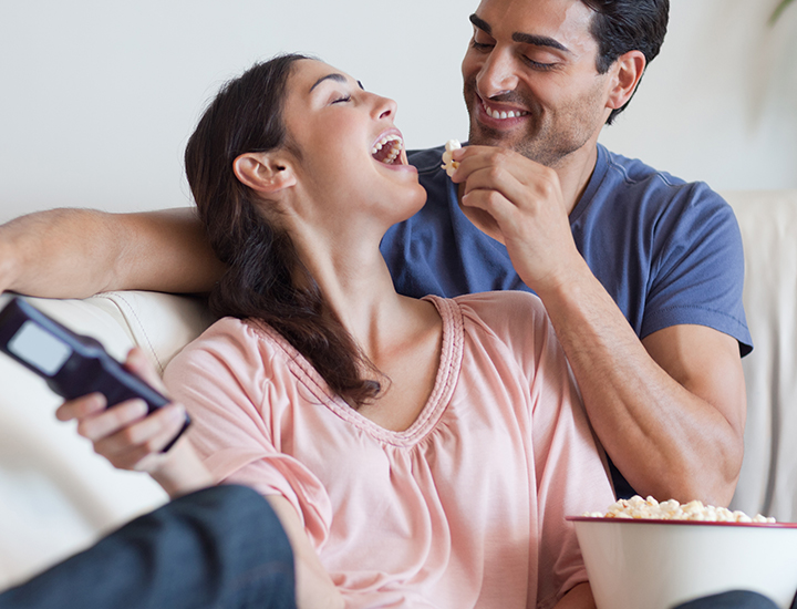 Couple eating popcorn on the couch