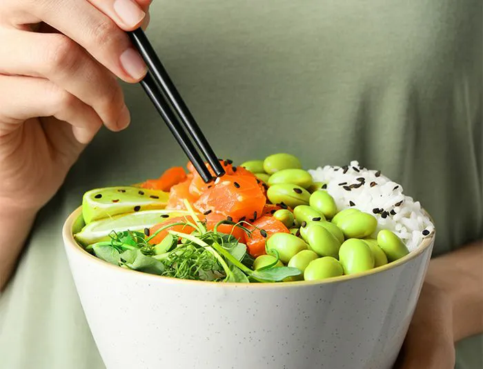 Person eating a bowl of roasted edamame