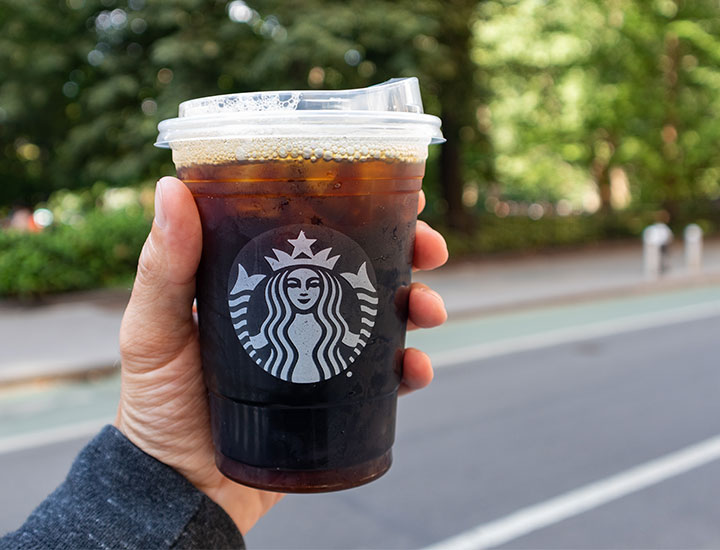 Hand holding a Starbucks cup with coffee in it in NYC