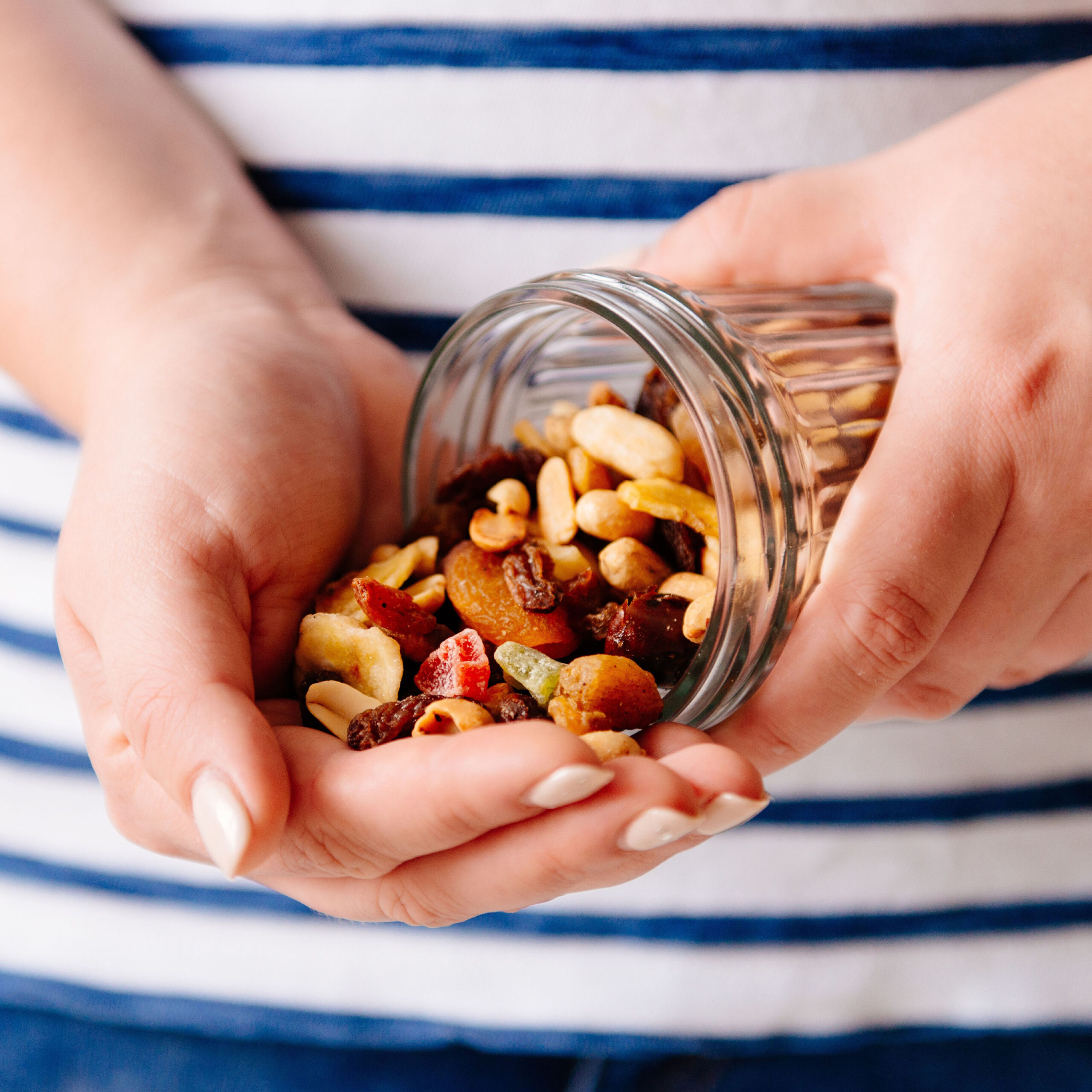 woman pouring handful of nuts and dried fruits into her hand