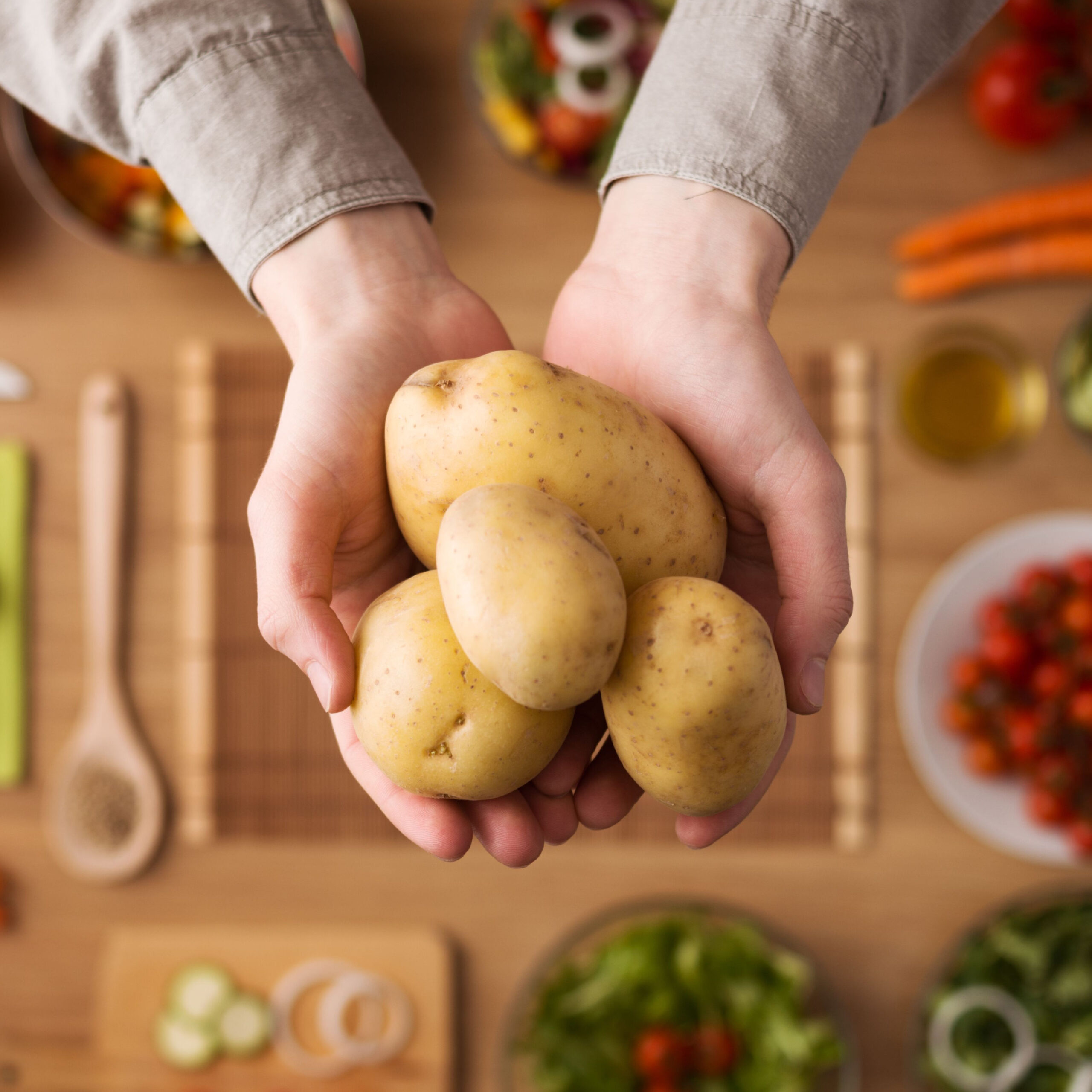 hands holding potatoes over table