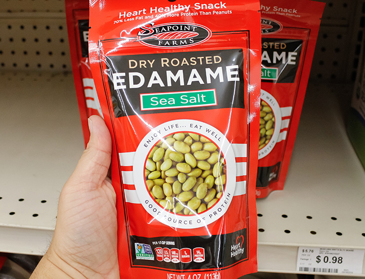 Person holding a bag of roasted edamame snack